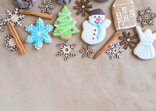 Gingerbread painted colored gingerbread cookies and spices and snowflakes on a craft background close-up. Christmas celebration concept. New Years food. Copy space