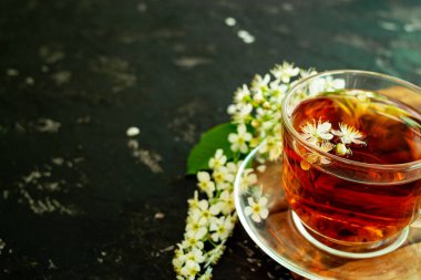 Siyah arka planda kiraz çiçekli bir fincan çiçek çayı. Boşluğu kopyala