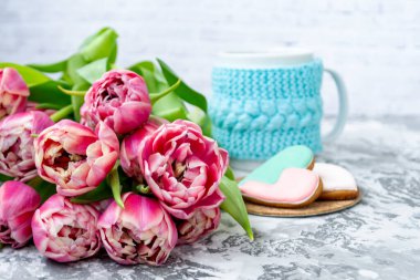 Bir buket pembe lale, bir fincan çay ve hafif arka planda kalp şeklinde zencefilli kurabiye. Uzayı kopyala Bahar tatili konsepti, Sevgililer Günü