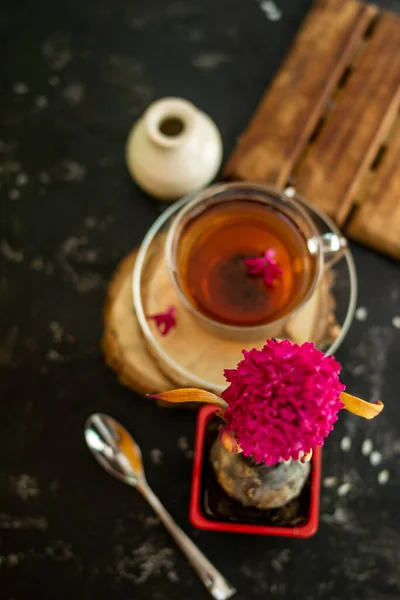 黒の背景に春のヒヤシンスの花と透明なカップの中にお茶のカップ マグカップは木製の枠の上にあり その横には金属製のスプーンと白い花瓶があります スペースのコピー — ストック写真