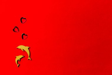 İki yunus, kırmızı arka planda kristal kalpli ahşap balık. Uzayı kopyala Sevgililer günü ve düğün