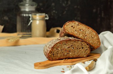 Tahtada siyah dilimlenmiş ekmek ve beyaz bir arka planda bıçak. Arka plan bulanık. Boşluğu kopyala.