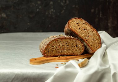 Tahtada siyah dilimlenmiş ekmek ve beyaz bir arka planda bıçak. Arka plan bulanık. Boşluğu kopyala.