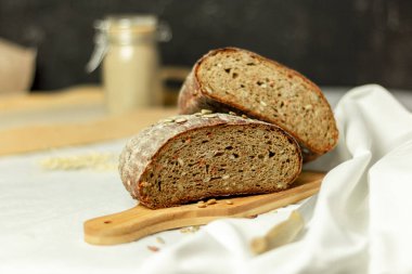 Tahtada siyah dilimlenmiş ekmek ve beyaz bir arka planda bıçak. Arka plan bulanık. Boşluğu kopyala.