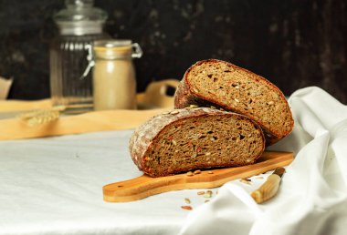 Tahtada siyah dilimlenmiş ekmek ve beyaz bir arka planda bıçak. Arka plan bulanık. Boşluğu kopyala.