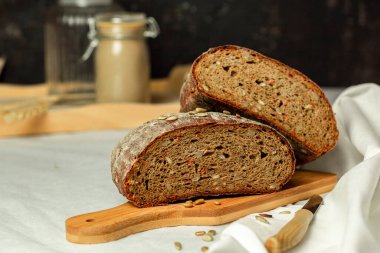 Tahtada siyah dilimlenmiş ekmek ve beyaz bir arka planda bıçak. Arka plan bulanık. Boşluğu kopyala.