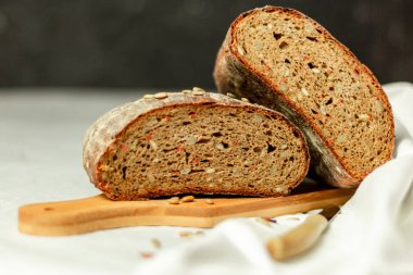 Tahtada siyah dilimlenmiş ekmek ve beyaz bir arka planda bıçak. Arka plan bulanık. Boşluğu kopyala.