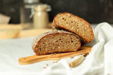 Tahtada siyah dilimlenmiş ekmek ve beyaz bir arka planda bıçak. Arka plan bulanık. Boşluğu kopyala.