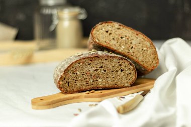 Tahtada siyah dilimlenmiş ekmek ve beyaz bir arka planda bıçak. Arka plan bulanık. Boşluğu kopyala.