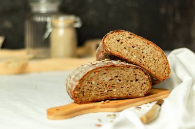 Tahtada siyah dilimlenmiş ekmek ve beyaz bir arka planda bıçak. Arka plan bulanık. Boşluğu kopyala