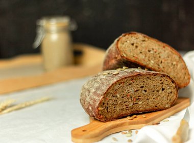 Tahtada siyah dilimlenmiş ekmek ve beyaz bir arka planda bıçak. Arka plan bulanık. Boşluğu kopyala