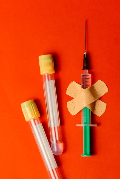 医学注射器は赤い背景に石膏で引っかかった。予防接種の概念。毒入りワクチンはない. — ストック写真