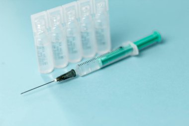 İğne için tıbbi şişeler, iğne için şırınga, mavi arka planda maske eldiveni. Giriş aşısı, grip aşısı..