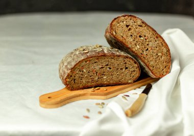 Tahtada siyah dilimlenmiş ekmek ve beyaz bir arka planda bıçak. Arka plan bulanık. Boşluğu kopyala.