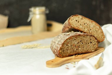 Tahtada siyah dilimlenmiş ekmek ve beyaz bir arka planda bıçak. Arka plan bulanık. Boşluğu kopyala.