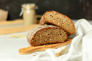 Tahtada siyah dilimlenmiş ekmek ve beyaz bir arka planda bıçak. Arka plan bulanık. Boşluğu kopyala.