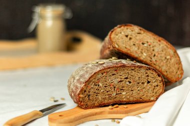 Tahtada siyah dilimlenmiş ekmek ve beyaz bir arka planda bıçak. Arka plan bulanık. Boşluğu kopyala.