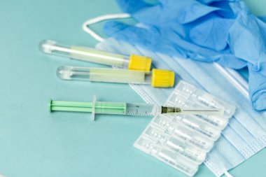 İğne için tıbbi şişeler, iğne için şırınga, mavi arka planda maske eldiveni. Giriş aşısı, grip aşısı.