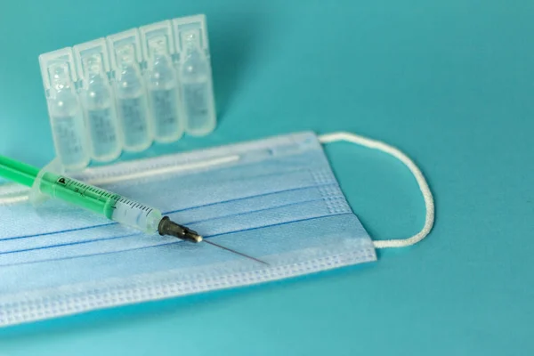 Medical vials for injection, syringe for injection, mask gloves on a blue background. Admission vaccination, flu shot.