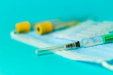 İğne için tıbbi şişeler, iğne için şırınga, mavi arka planda maske eldiveni. Giriş aşısı, grip aşısı.