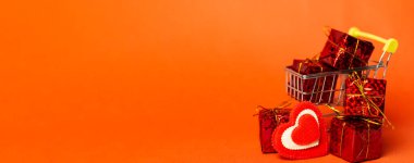 Hediye kutulu alışveriş arabası, aşk kalbi ve kırmızı arka planda yer. Sevgililer Günü alışverişi ve satışı. Uzun pankart