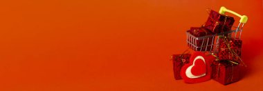 Hediye kutulu alışveriş arabası, aşk kalbi ve kırmızı arka planda yer. Sevgililer Günü alışverişi ve satışı. Uzun pankart