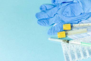 İğne için tıbbi şişeler, iğne için şırınga, mavi arka planda maske eldiveni. Giriş aşısı, grip aşısı.