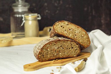 Tahtada siyah dilimlenmiş ekmek ve beyaz bir arka planda bıçak. Arka plan bulanık. Boşluğu kopyala.