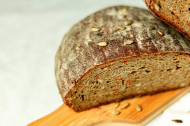 Tahtada siyah dilimlenmiş ekmek ve beyaz bir arka planda bıçak. Arka plan bulanık. Boşluğu kopyala.