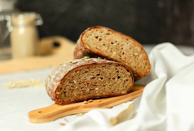 Tahtada siyah dilimlenmiş ekmek ve beyaz bir arka planda bıçak. Arka plan bulanık. Boşluğu kopyala.