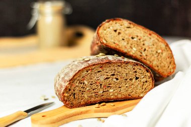 Tahtada siyah dilimlenmiş ekmek ve beyaz bir arka planda bıçak. Arka plan bulanık. Boşluğu kopyala.