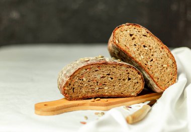 Tahtada siyah dilimlenmiş ekmek ve beyaz bir arka planda bıçak. Arka plan bulanık. Boşluğu kopyala.