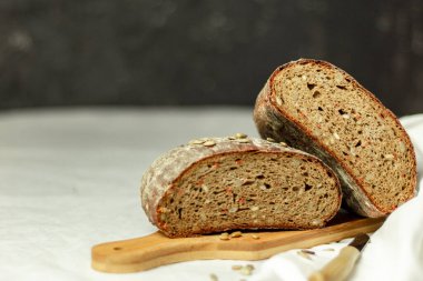 Tahtada siyah dilimlenmiş ekmek ve beyaz bir arka planda bıçak. Arka plan bulanık. Boşluğu kopyala.