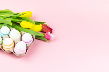 Paskalya, pembe arka planda lalelerle boyanmış yumurtalar. Uzayı kopyala Paskalya kutlaması kavramı