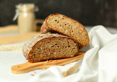Tahtada siyah dilimlenmiş ekmek ve beyaz bir arka planda bıçak. Arka plan bulanık. Boşluğu kopyala.
