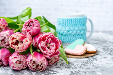 Bir buket pembe lale, bir fincan çay ve hafif arka planda kalp şeklinde zencefilli kurabiye. Uzayı kopyala Bahar tatili konsepti, Sevgililer Günü