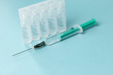 İğne için tıbbi şişeler, iğne için şırınga, mavi arka planda maske eldiveni. Giriş aşısı, grip aşısı..