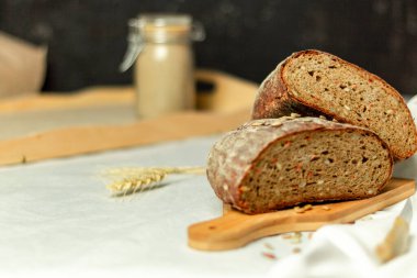 Tahtada siyah dilimlenmiş ekmek ve beyaz bir arka planda bıçak. Arka plan bulanık. Boşluğu kopyala.