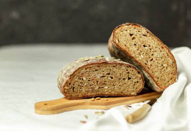 Tahtada siyah dilimlenmiş ekmek ve beyaz bir arka planda bıçak. Arka plan bulanık. Boşluğu kopyala.