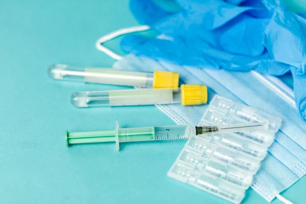 Medical vials for injection, syringe for injection, mask gloves on a blue background. Admission vaccination, flu shot