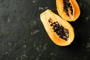 Siyah desenli arka planda dilimlenmiş taze ve lezzetli papaya. Tropik meyve. Boşluğu kopyala.