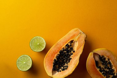 Dilimlenmiş taze ve lezzetli papaya ve sarı arka planda yeşil limon. Tropik meyve. Boşluğu kopyala
