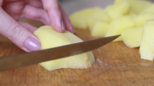 As mãos dos chefs estão cortando batatas com uma faca grande em uma tábua de corte. O homem está a cortar vegetais. Cozinhar comida deliciosa, close-up. — Vídeo de Stock