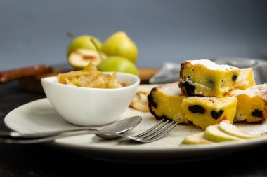 Beyaz bir tabakta dilimlenmiş turta ve siyah bir masada armut reçeli. Arka plandaki yeşil armutlar bulanık. Sabah kahvaltısı.