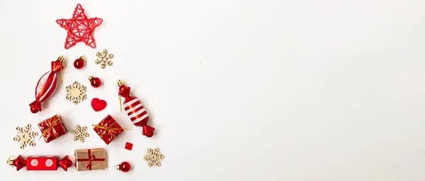 Farklı nesnelerden, kar tanelerinden, hediyelerden, beyaz arka planda şekerlerden oluşan bir Noel ağacının düz kompozisyonu. Boşluğu kopyala.
