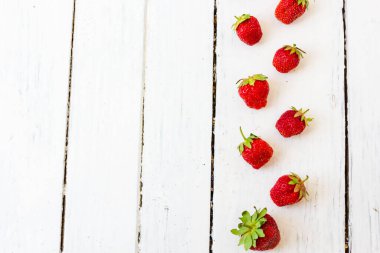 Olgun kırmızı çilek, ahşap beyaz arka plandaki çerçeve gibi bir desen içinde yatar. Uzayı kopyala Yukarıdan görüntüle