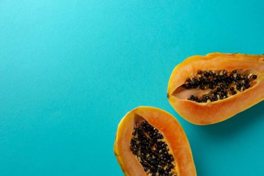 Yaz kompozisyonu. İkiye bölünmüş tropikal papaya meyveleri mavi arka planda yatar. Yaz kavramı. Düz konum, üst görünüm, kopyalama alanı.