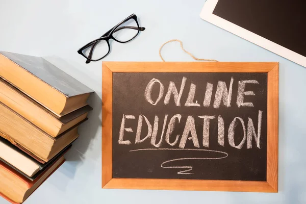 Chalk board - online learning, tablet and a stack of books. Remote education concept.