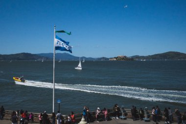 San Francisco, ABD: 30 Mart 2019: Balıkçı İskelesi 'nden geçen tekneyi izleyen insanlar