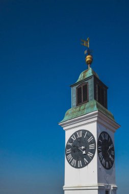 Sırbistan 'ın Novi Sad kentinde Petrovaradin Kalesi' nin saat kulesi mavi gökyüzüne karşı